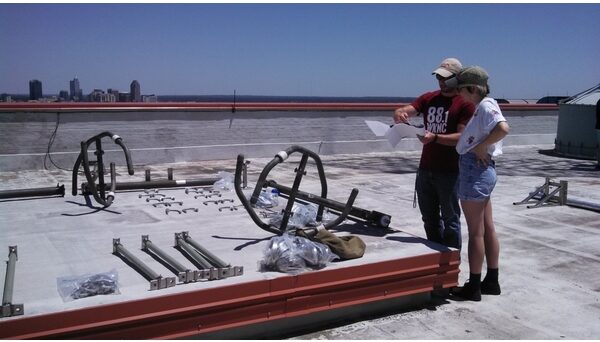 Student Media IT Manager Doug Flowers shows General Manager Emily Ehling pieces of the WKNC antenna on the roof of D.H. Hill Library. WKNC reconfigured its antenna pattern in June 2016 to reach further southeast toward Goldsboro and Wilmington. Photo by Jamie Lynn Gilbert.