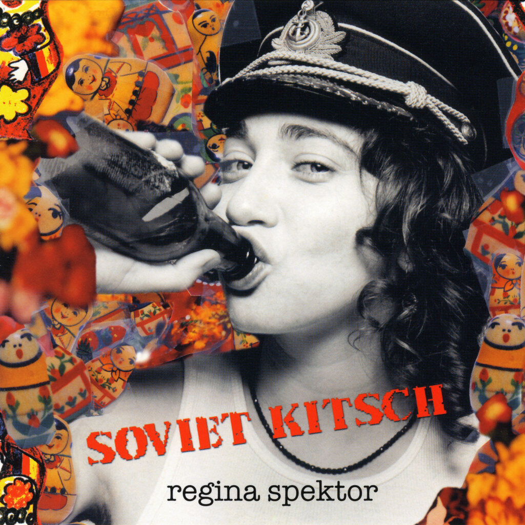 A smirking Regina Spektor drinks vodka amid a background of Russian nesting dolls on the album cover of Soviet Kitsch