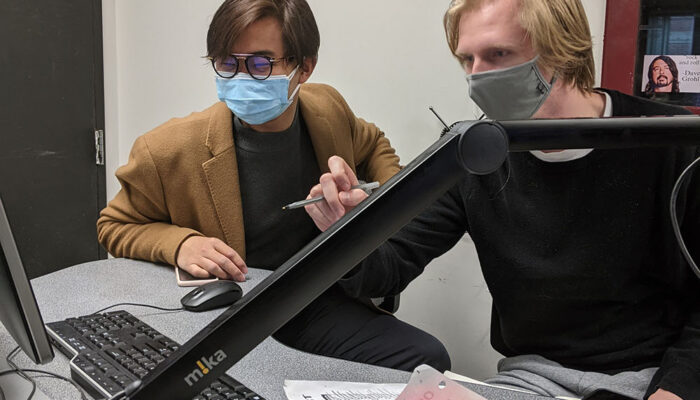 DJ Ethan Myers, right, shows trainee Curtis Cheung how to log songs on Spinitron.