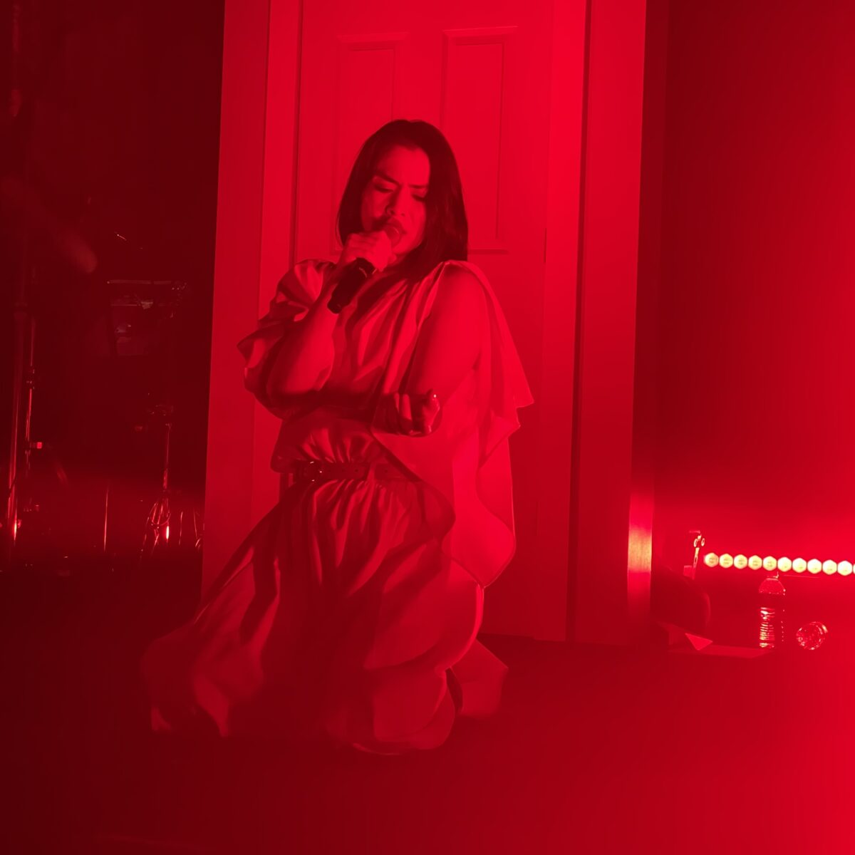Mitski on stage, coated in red lighting.