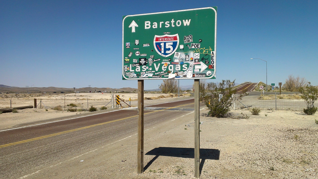 Photo of Barstow road sign that also points to Las Vegas and is surrounded by desert. 