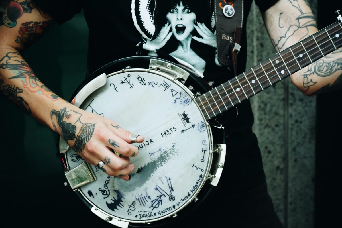 A person with tattoos playing the banjo.
