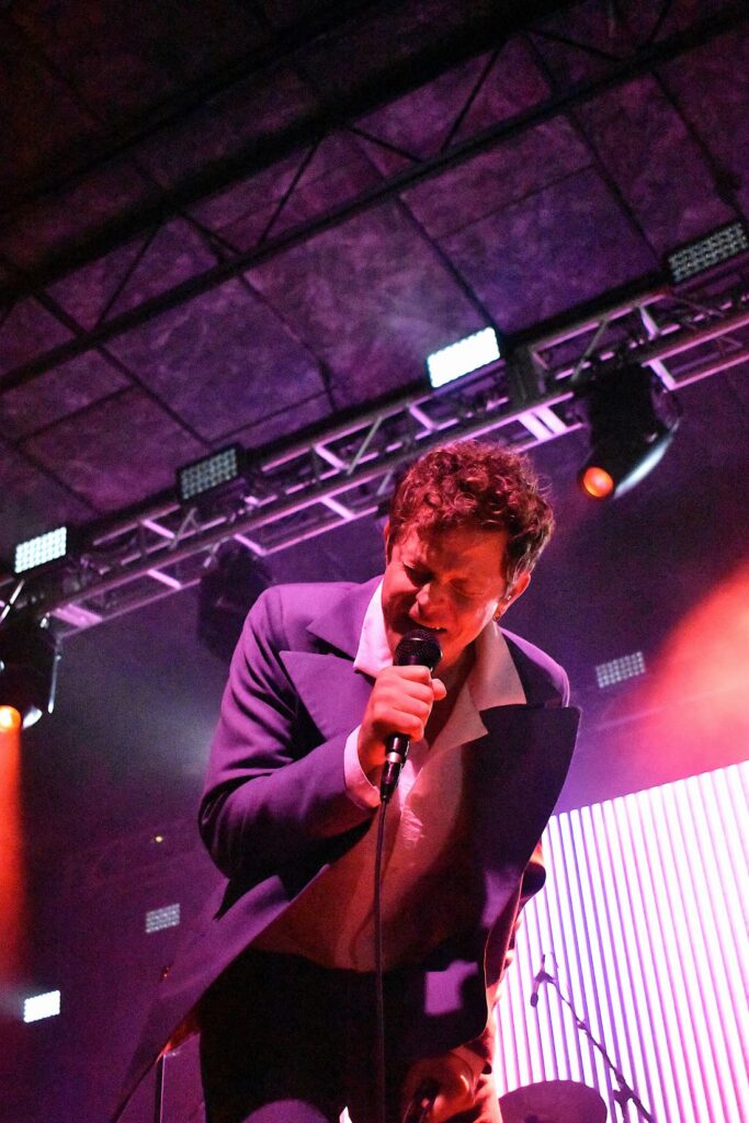 Mike Hadreas bent over with his faced scrunched up belting his songs into a mic.