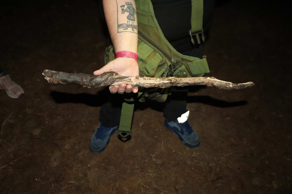 A woman holding an engraved wand made entirely of wood.