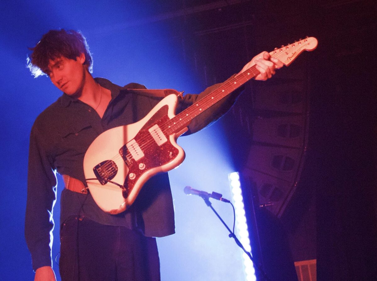 Photo of a guitarist holding their guitar on stage.