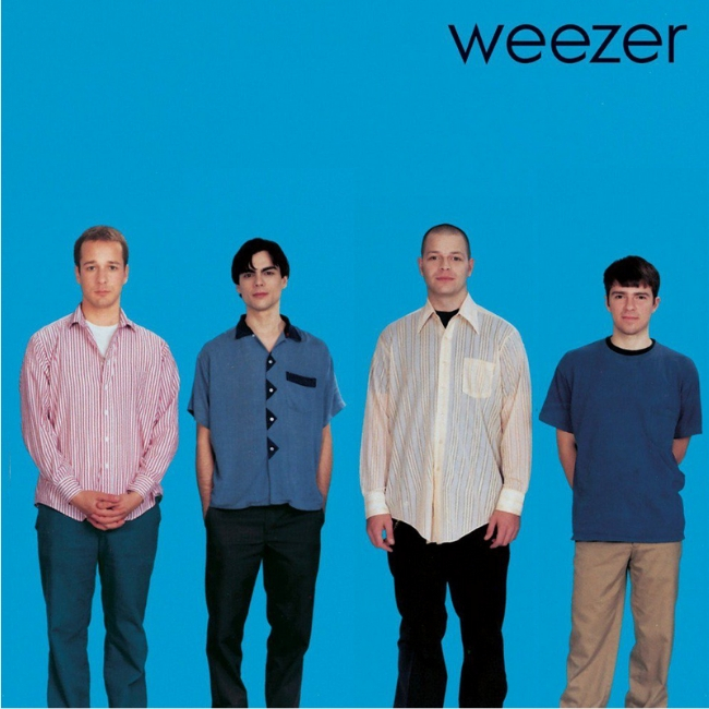 The album cover of "The blue album" by Weezer. It features the members of Weezer standing in front of a solid blue background with the word "weezer" in the corner