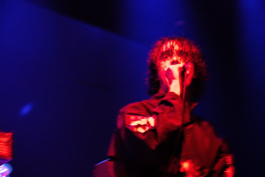 Matt Stephenson of Machine Girl singing into a mic on stage at The Ritz.