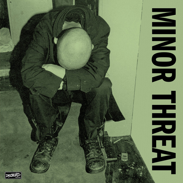 Minor Threat album cover for First Two Seven Inches. A man sitting with his head on his arms in a stairwell.