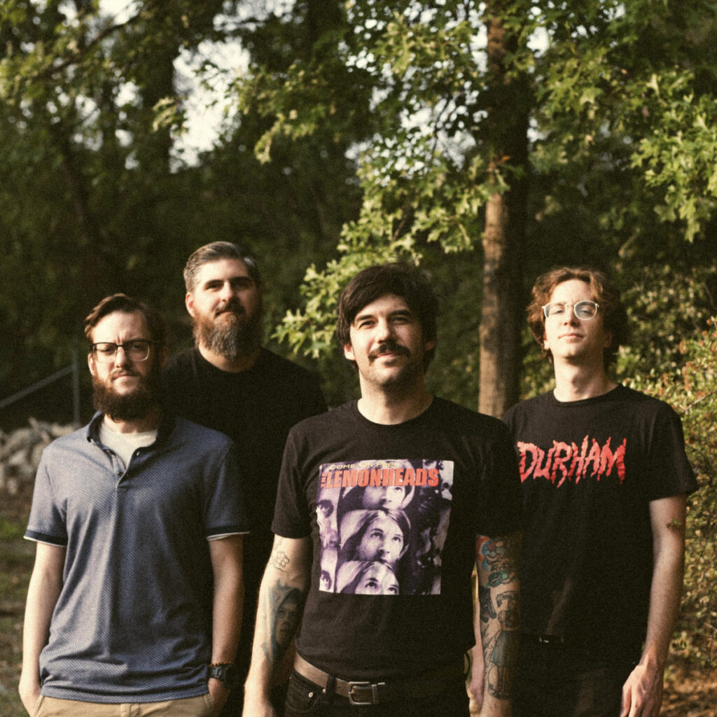 Four members of the band Boy Named Sue standing in a wooded area.