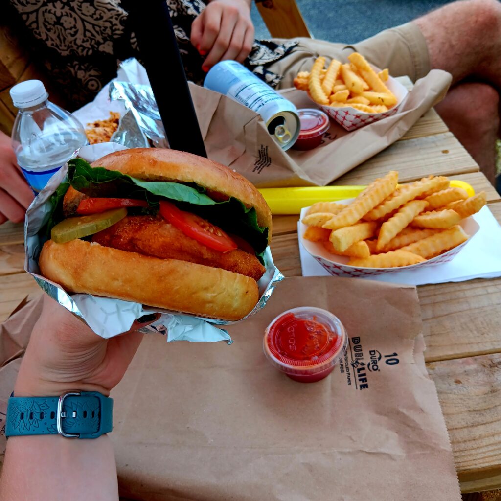 Perfect looking chicken sandwich in foil wrapper with crinkle cut fries and Ketchup in the background.