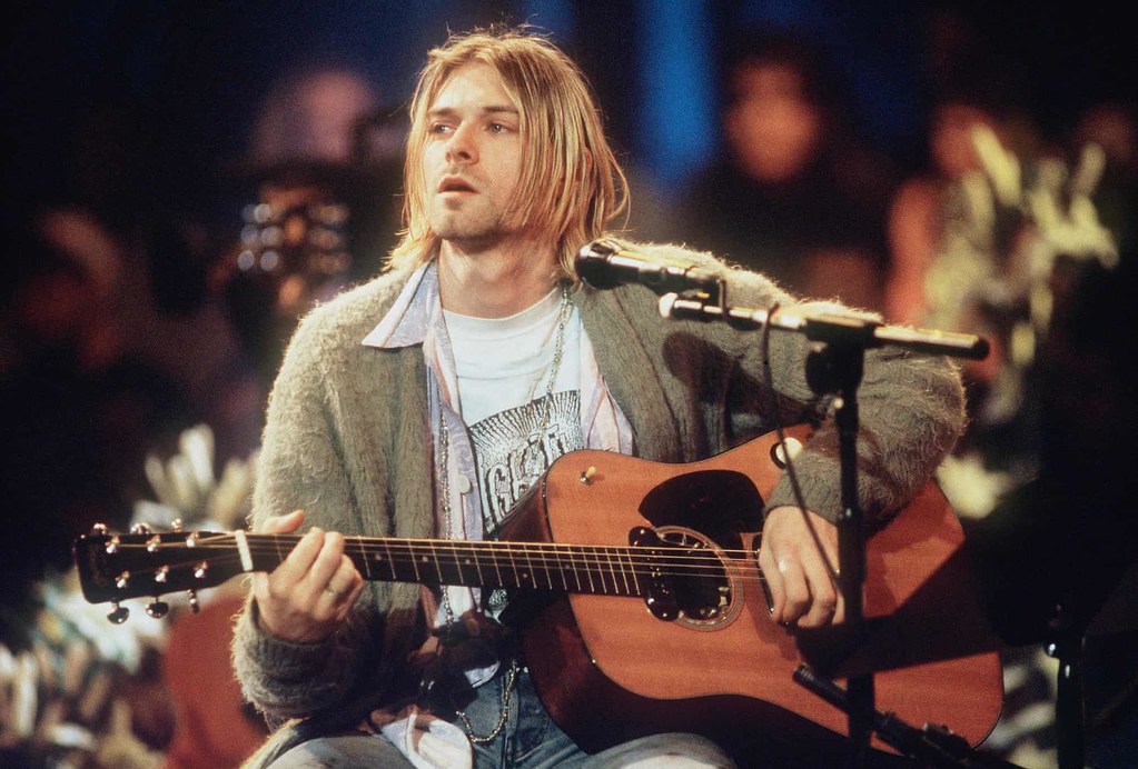 Young man sitting at microphone with acoustic guitar