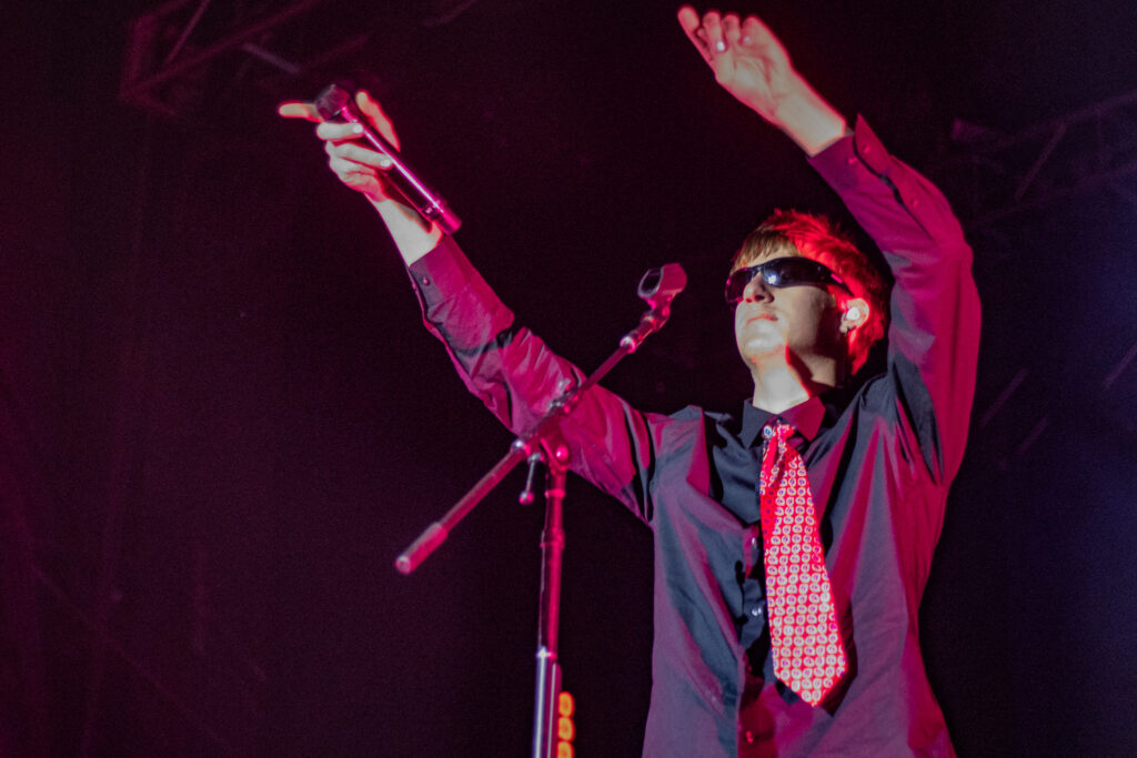 Malcolm Todd dances with microphone in hand pointing it towards the crowd.