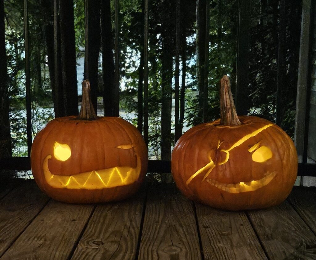 Two carved pumpkins. Left one with a winky face and a whimsically creepy smile. Right one with a toothy grin, an eye patch and some missing teeth