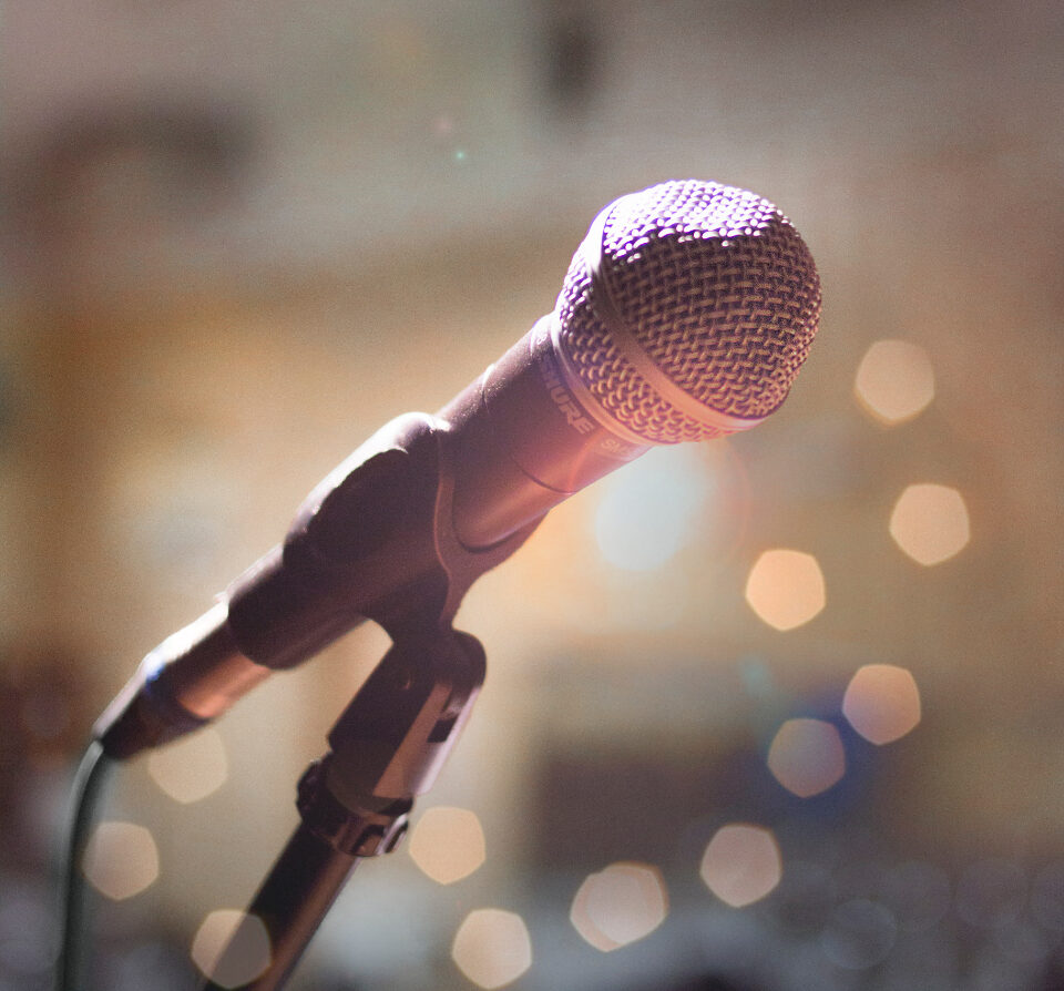 Modern microphone on a stand with warm lighting in a blurry background
