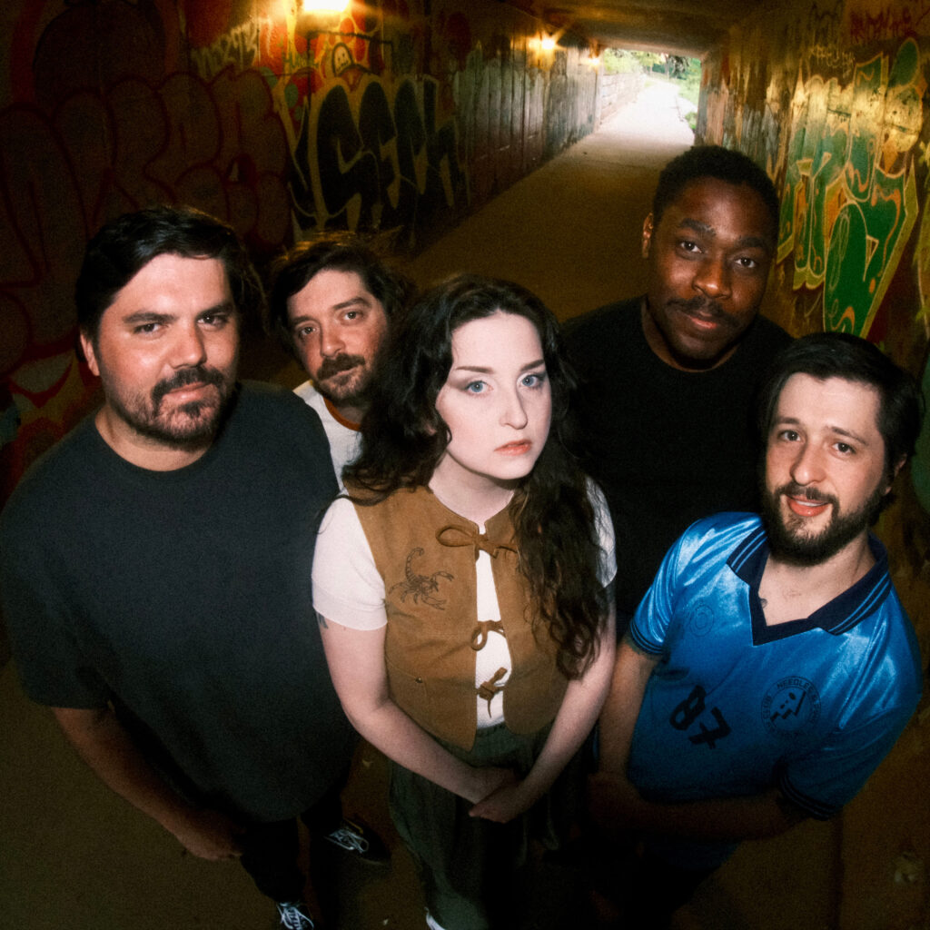 Five members of the band Petrov in a graffitied tunnel.