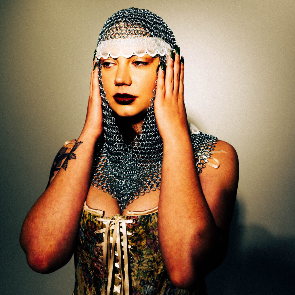 CJ Monet in corset and chainmail head scarf.