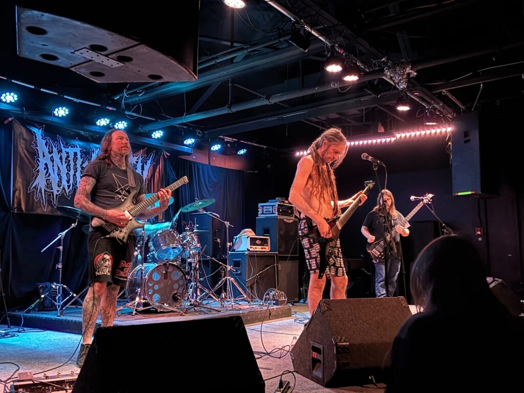 Noctomb illuminated by normal white stage lights, sound-checking before their performance. By Killian Le, used by permission.