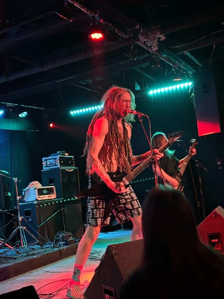 Close up of a long, shaggy-haired man, shirtless and dressed in gym shorts. By Killian Le, used by permission.