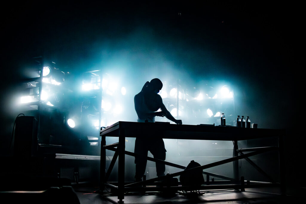 Snow Strippers' Graham Perez behind a table DJing.