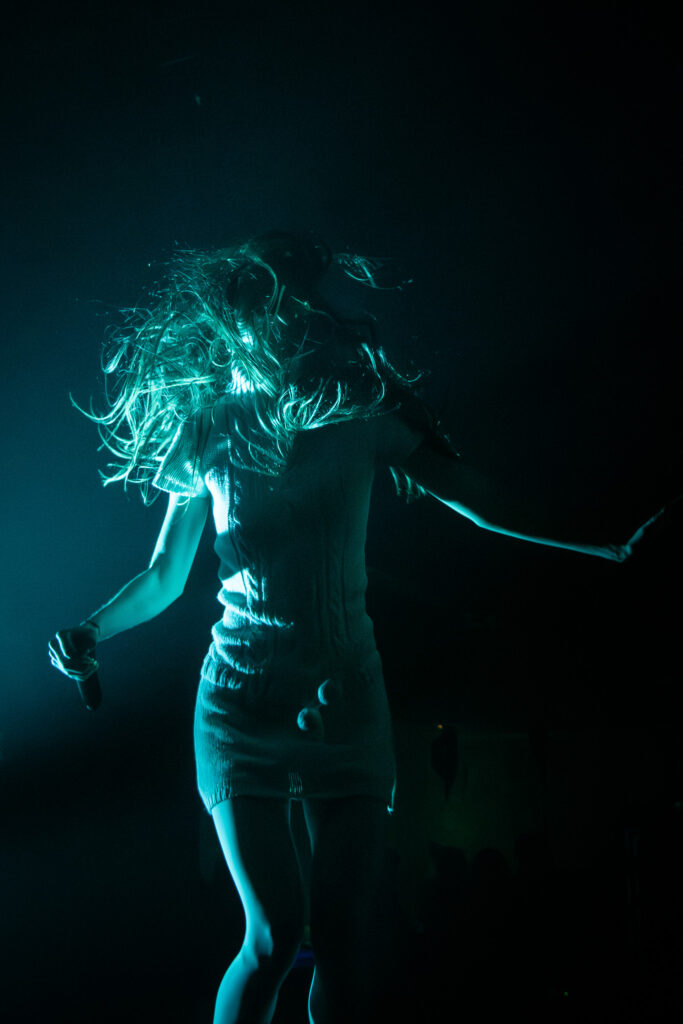 Snow Strippers' Tatiana Schwainger tossing hair around in teal light.