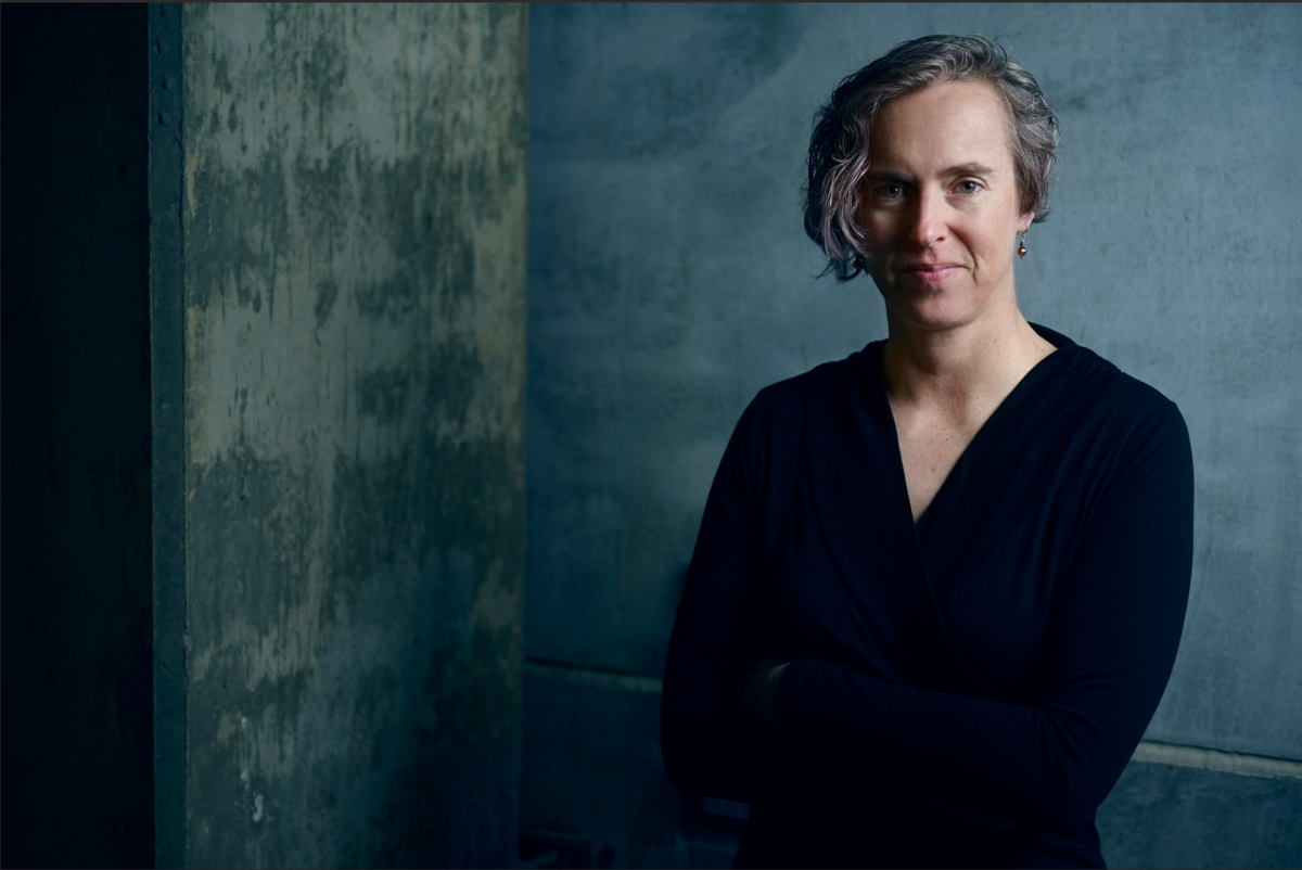 Woman in black posing in front of grey background