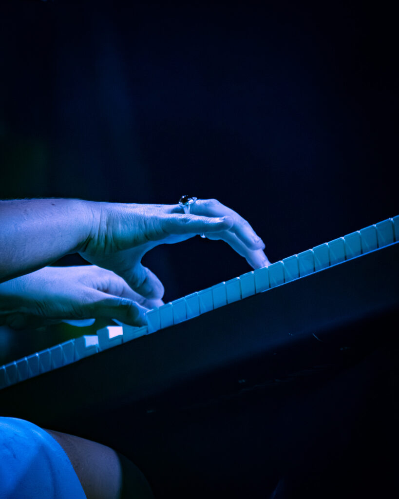 Madison Cunningham's hands on piano keys in blue lighting.