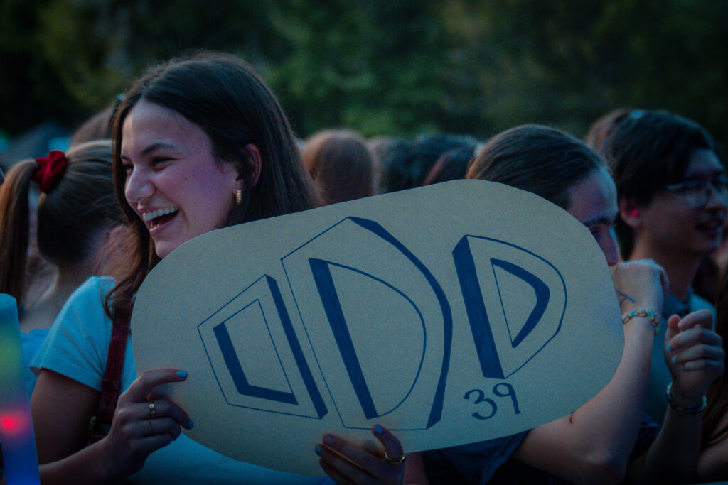 Odd 39 fans with a sign held up smiling. 