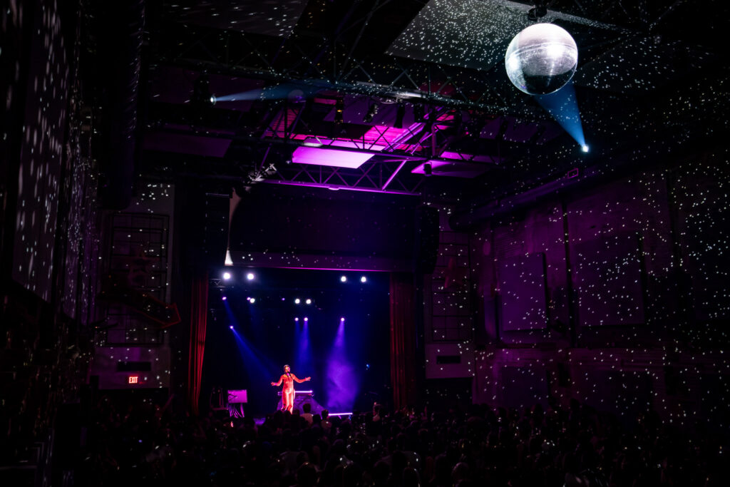 Alice Phoebe Lou on stage with a large Disco ball lighting up the room.