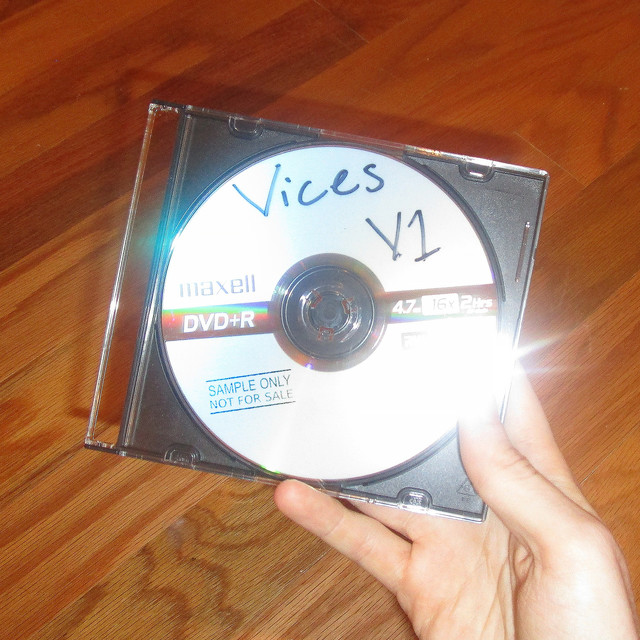 A shoddily done photo of a blank cd in a generic jewel case. It is labeled "Vices V1"